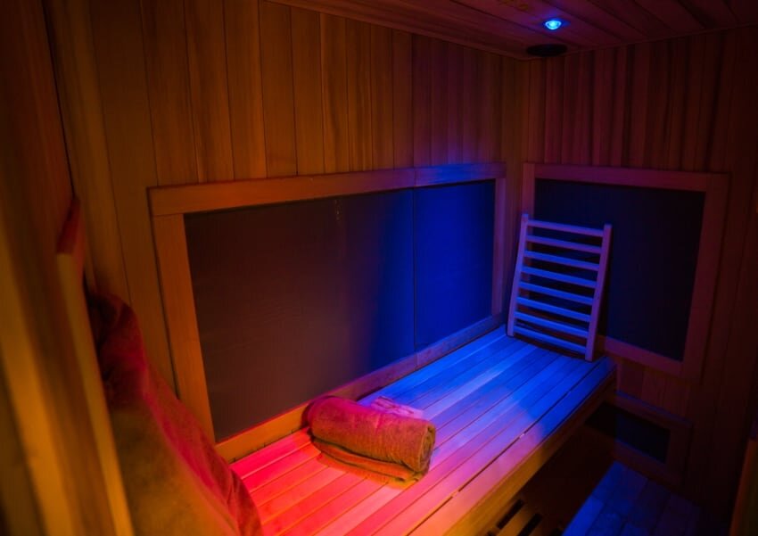Interior of our full spectrum infrared sauna glowing with red and blue chromotherapy lighting